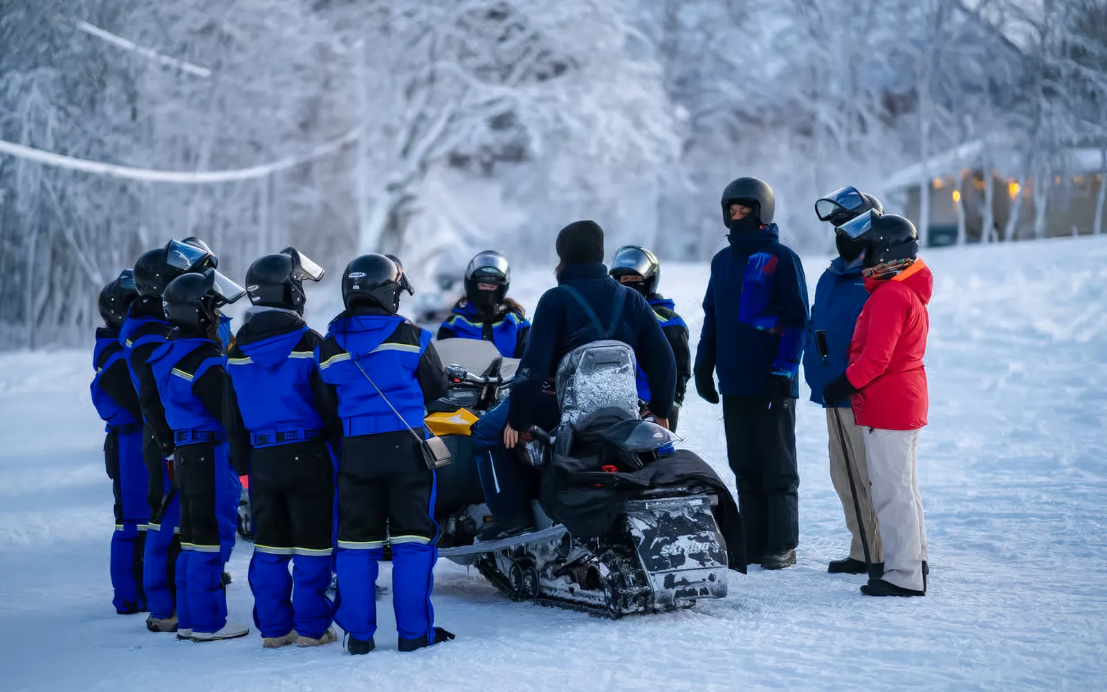 Group preparing for snowmobile ride in snowy Tromso landscape.