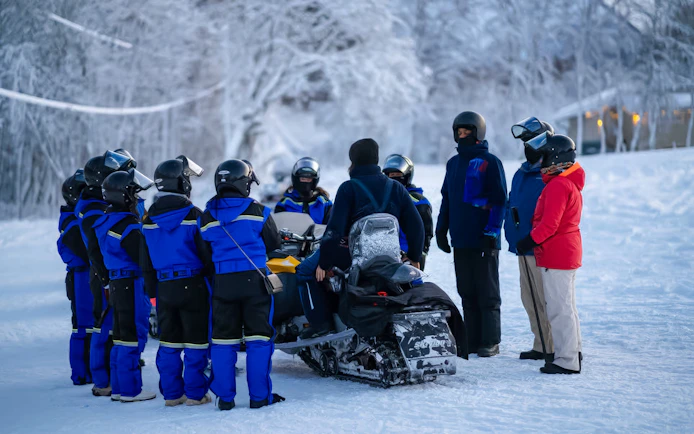 Group preparing for snowmobile ride in snowy Tromso landscape.
