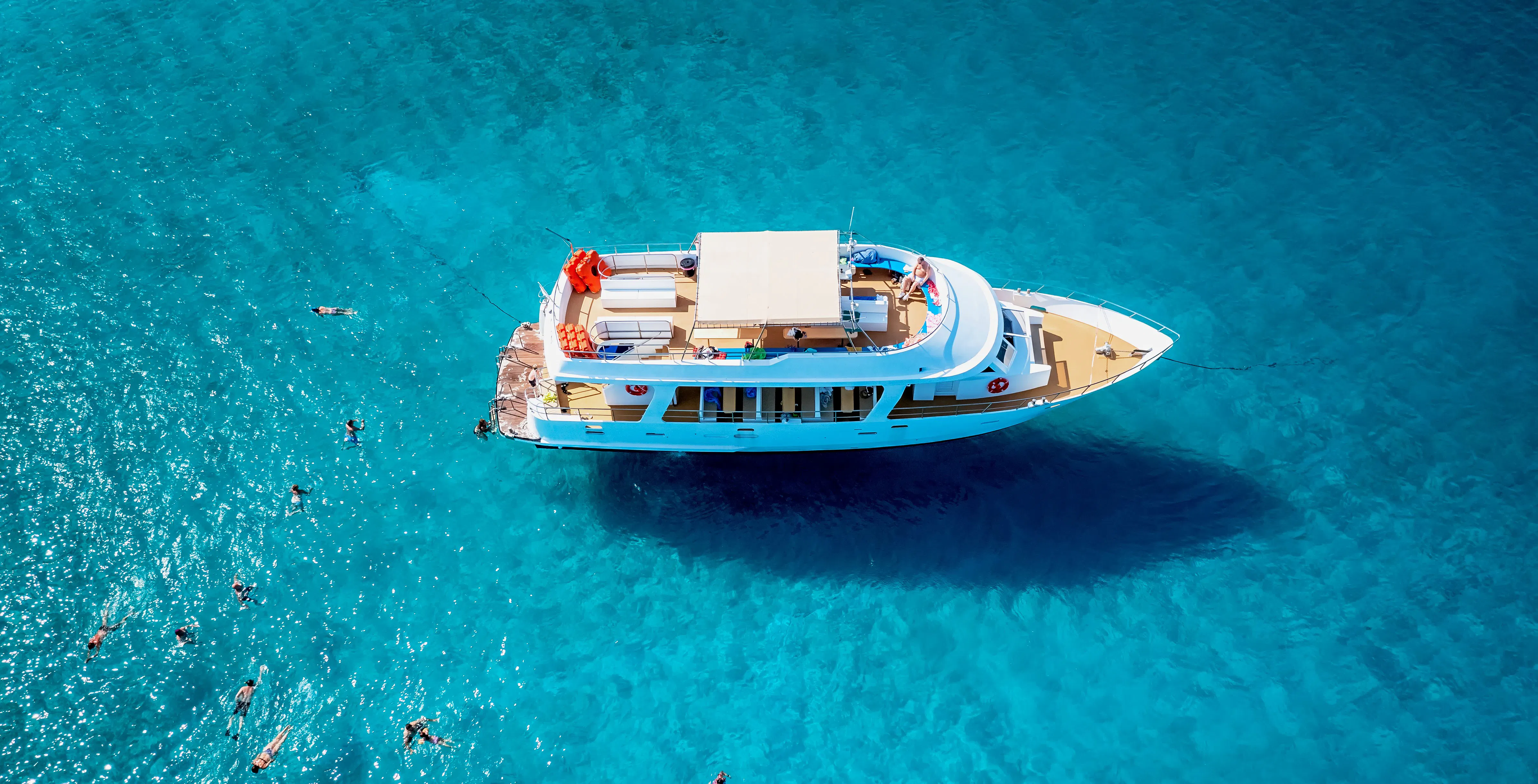 Cruise boat with swimming tourists in Blue Lagoon, Latchi, Paphos District, Cyprus.