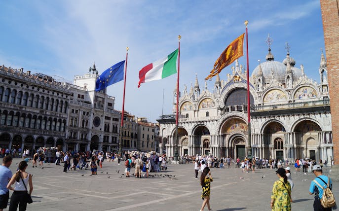 St. Mark's Basilica and flags in Venice's Piazza San Marco, Italy.