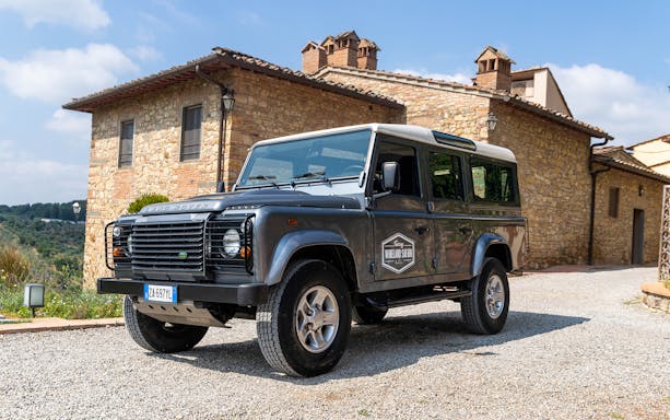 Land Rover parked in front of a stone villa in Tuscany for a wineland safari tour.