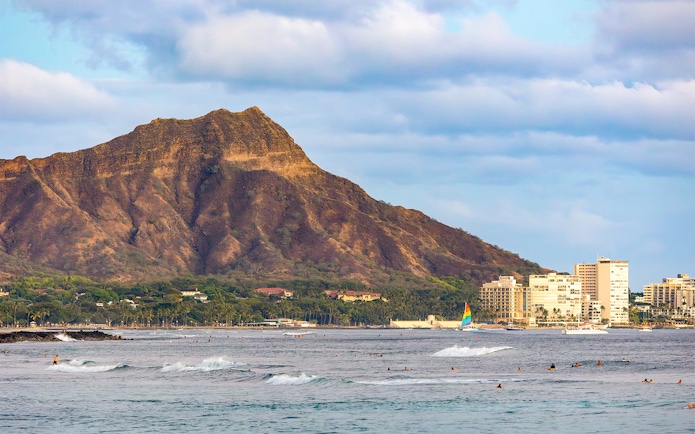 Surfers in the ocean with Leahi Diamond Head at sunset, Honolulu, Oahu, Hawaii.