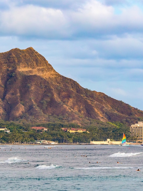 Surfers in the ocean with Leahi Diamond Head at sunset, Honolulu, Oahu, Hawaii.