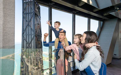 Family enjoying view from Chicago 360 Observation Deck with city skyline.