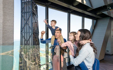 Family enjoying view from Chicago 360 Observation Deck with city skyline.