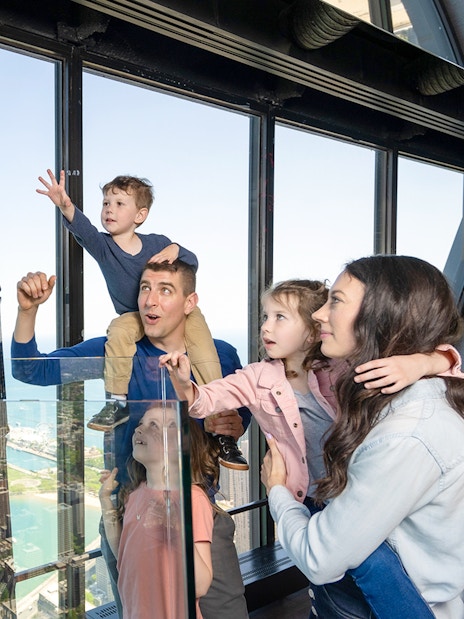 Family enjoying view from Chicago 360 Observation Deck with city skyline.