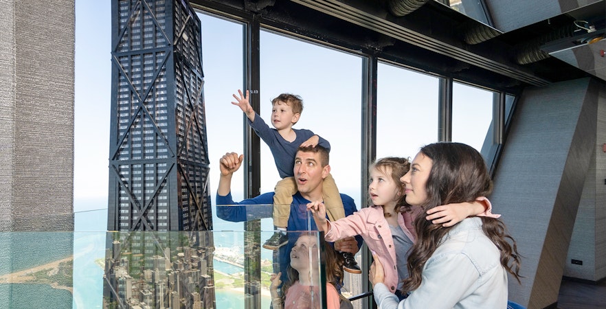 Family enjoying view from Chicago 360 Observation Deck with city skyline.