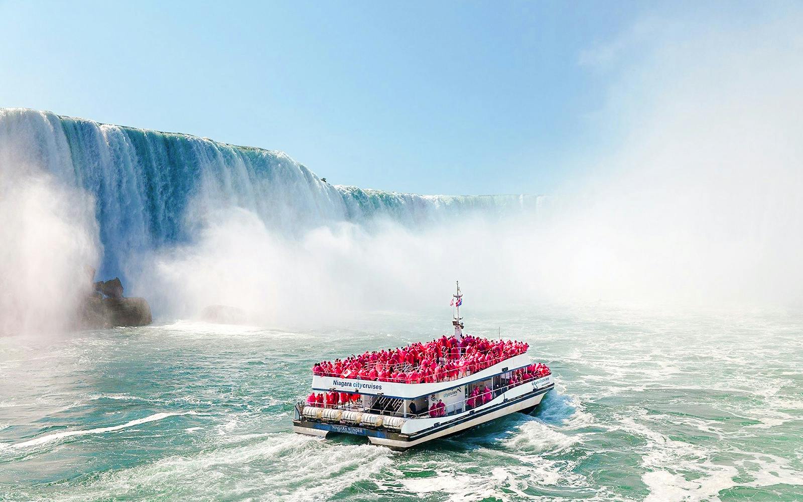 Boat tour approaching Niagara Falls, Canada with passengers in red ponchos.