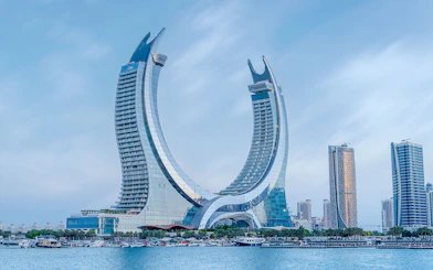 Crescent-shaped skyscraper in Qatar with waterfront view.