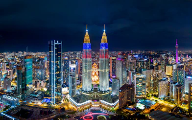 Kuala Lumpur skyline at night featuring the illuminated Petronas Twin Towers.