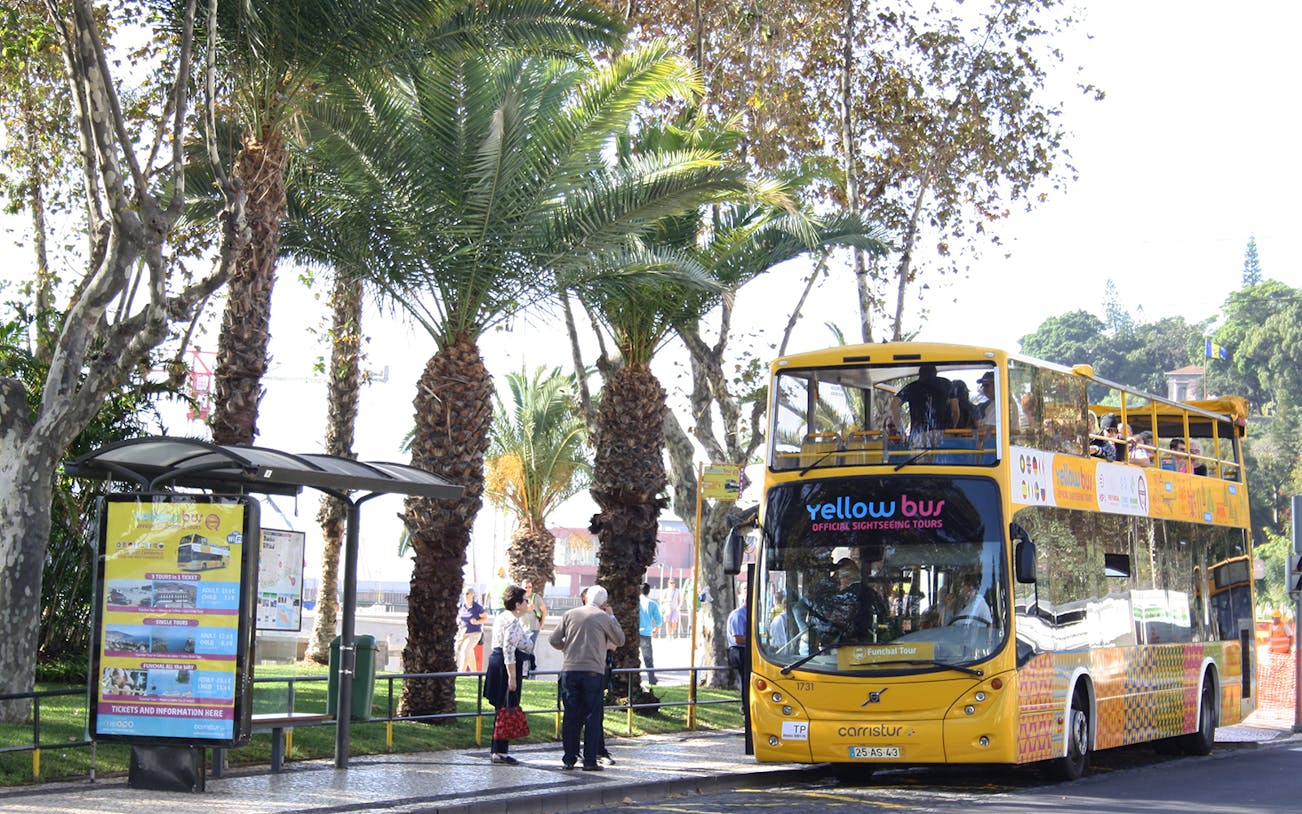 Open-top yellow bus at Funchal stop for 48-hour hop-on hop-off tour.