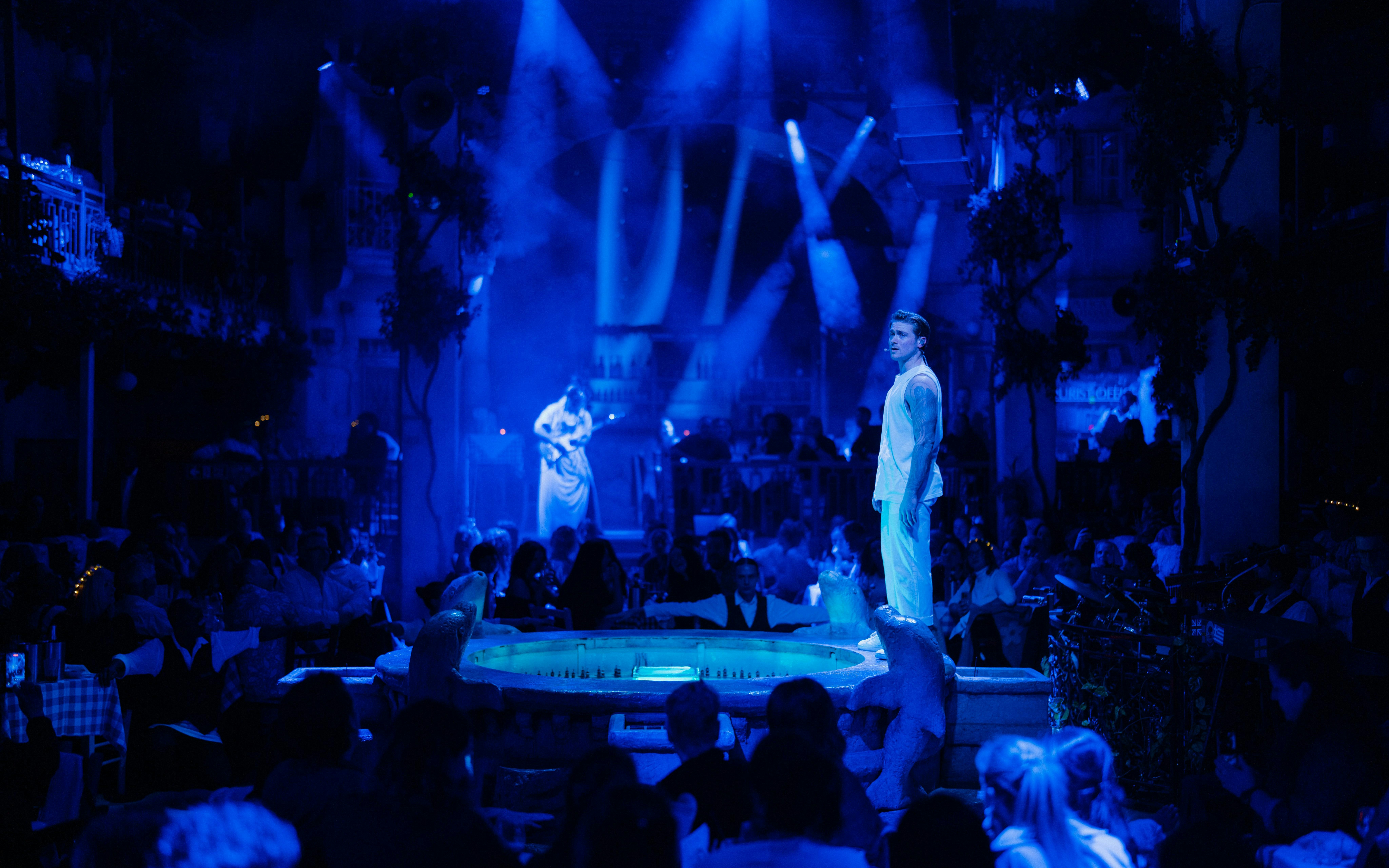 Performer on stage during Mamma Mia! The Party with audience in a vibrant setting.