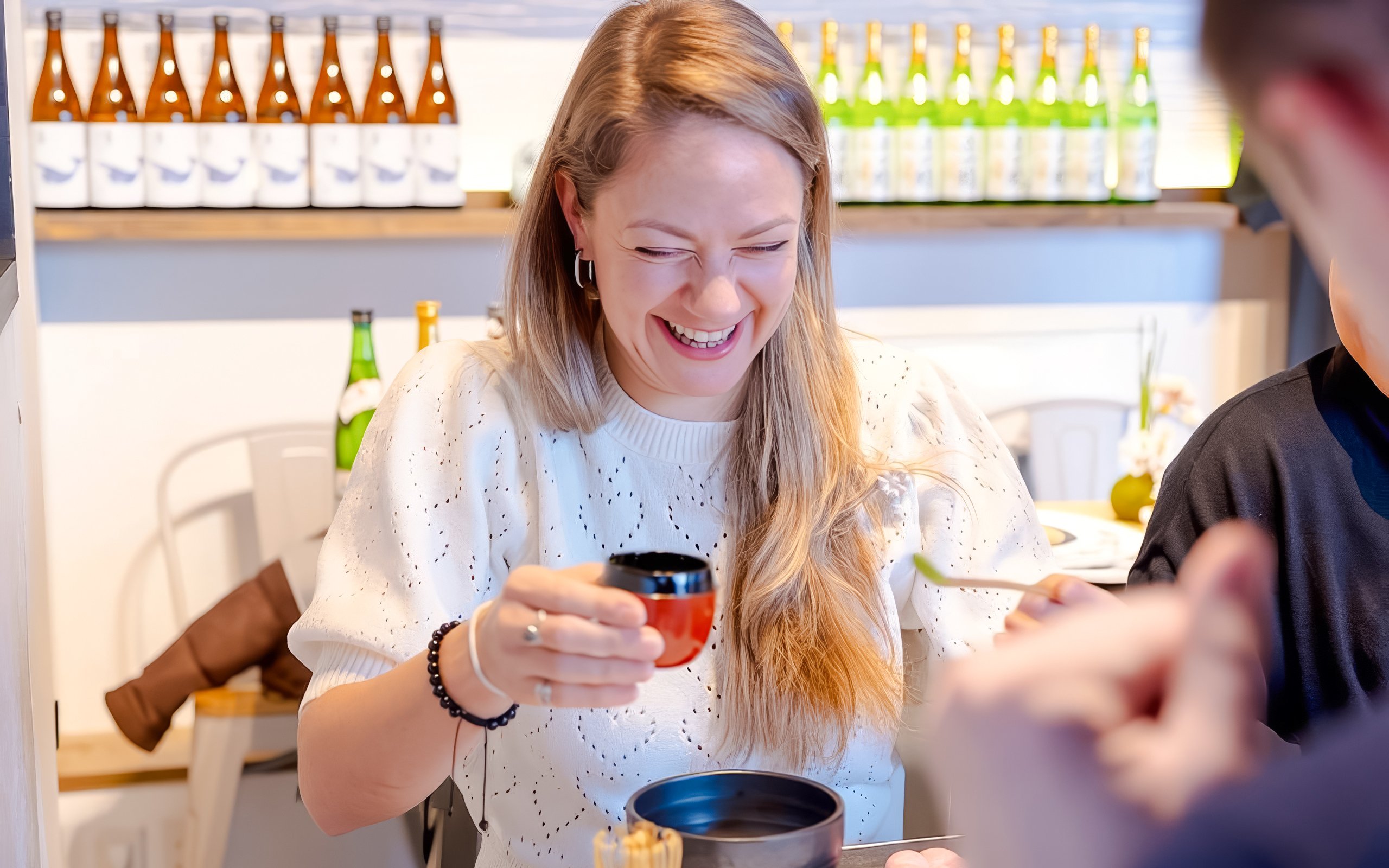 Tourist enjoying matcha-making experience with Japanese sweets in Tokyo.