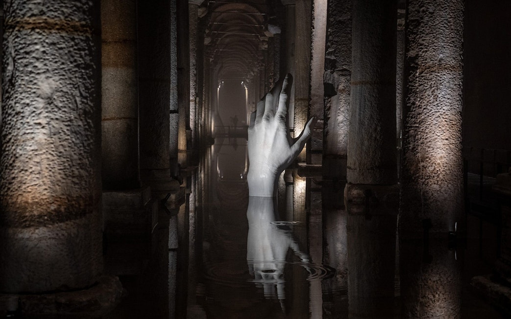 Basilica Cistern interior with illuminated columns and submerged hand sculpture, Istanbul.
