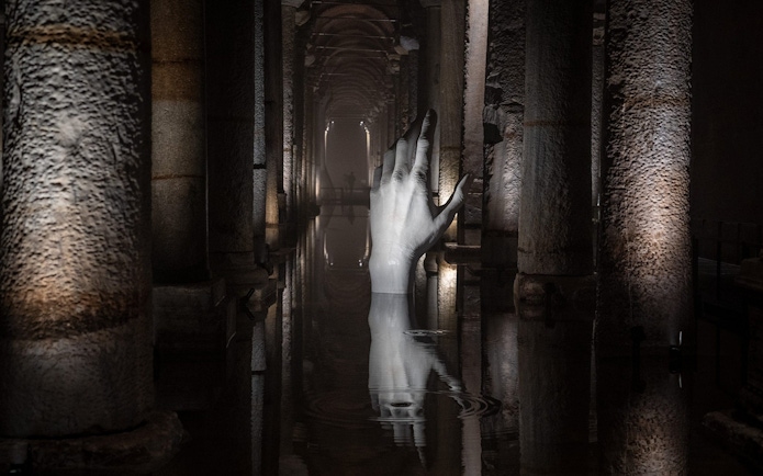 Basilica Cistern interior with illuminated columns and submerged hand sculpture, Istanbul.