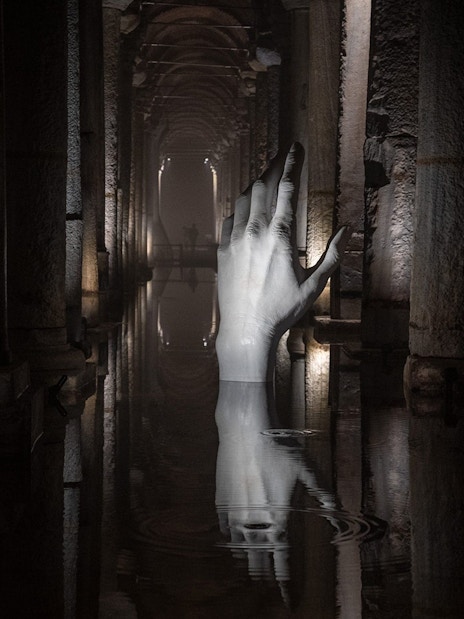 Basilica Cistern interior with illuminated columns and submerged hand sculpture, Istanbul.