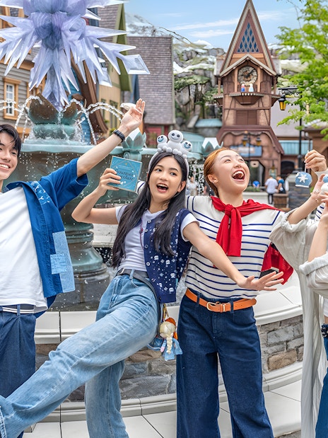 Friends enjoying at Disneyland Hong Kong near a themed fountain.