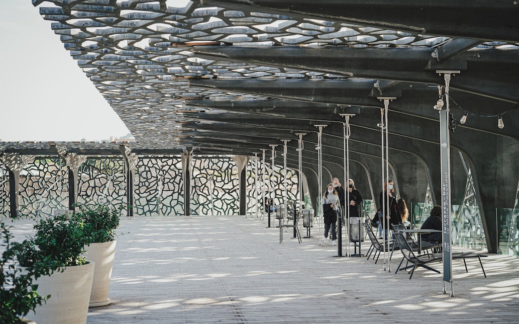 Mucem Marseille terrace with visitors walking under intricate lattice roof.