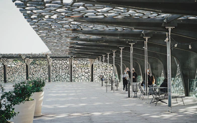 Mucem Marseille terrace with visitors walking under intricate lattice roof.