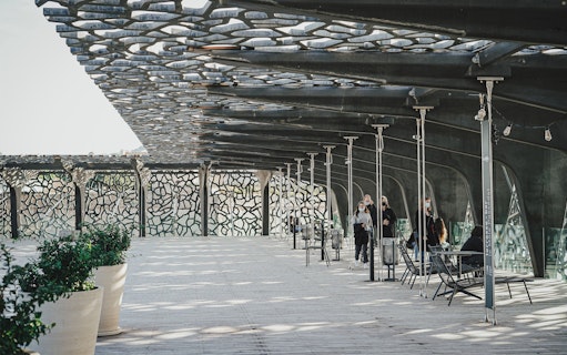 Mucem Marseille terrace with visitors walking under intricate lattice roof.