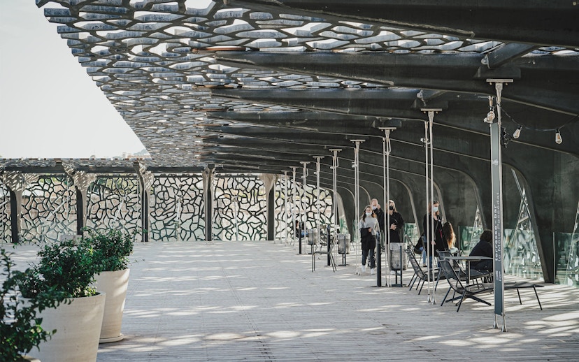 Mucem Marseille terrace with visitors walking under intricate lattice roof.