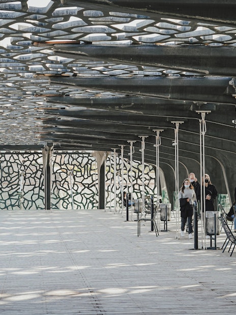 Mucem Marseille terrace with visitors walking under intricate lattice roof.