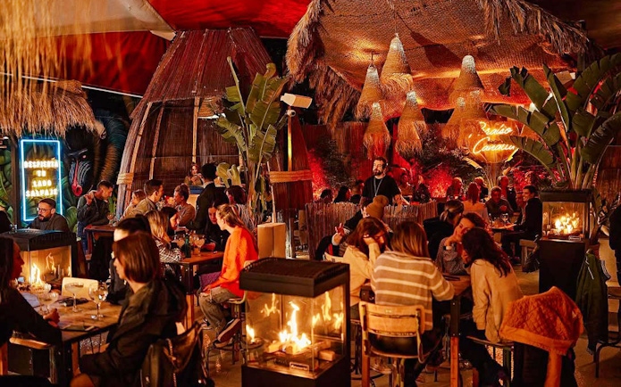 Guests dining at Baloo Ibiza with tropical decor and ambient lighting.