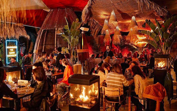 Guests dining at Baloo Ibiza with tropical decor and ambient lighting.