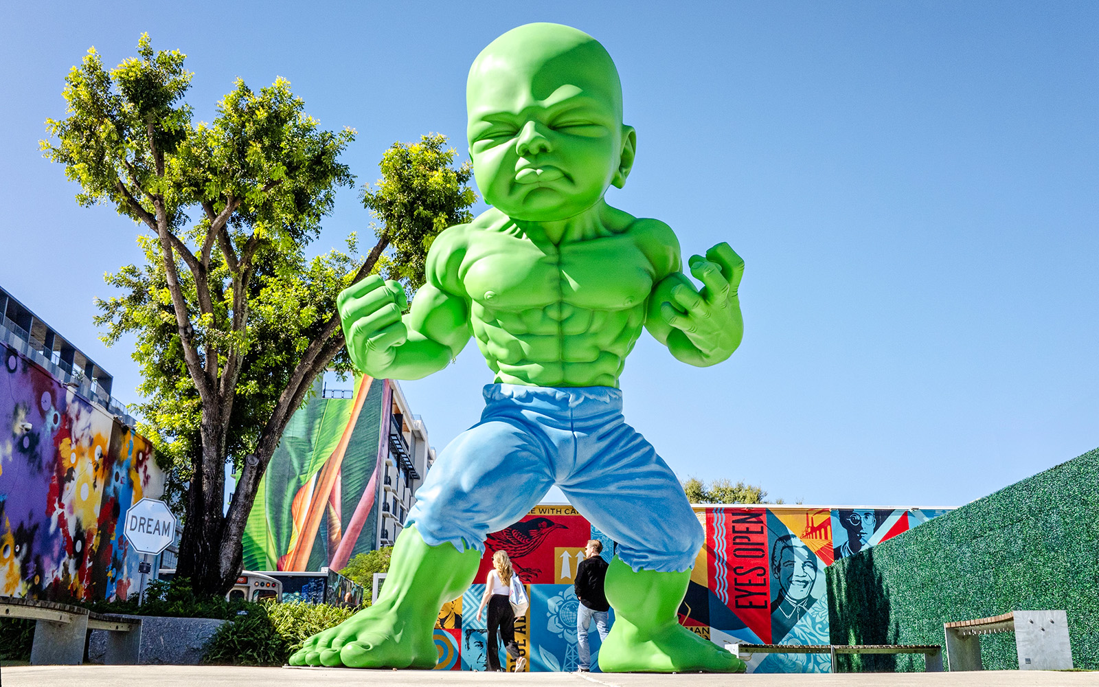 Giant green sculpture at Wynwood Walls Museum with colorful murals in Miami.