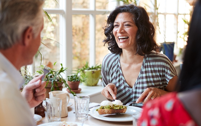 Woman enjoying brunch with friends in a bright cafe.