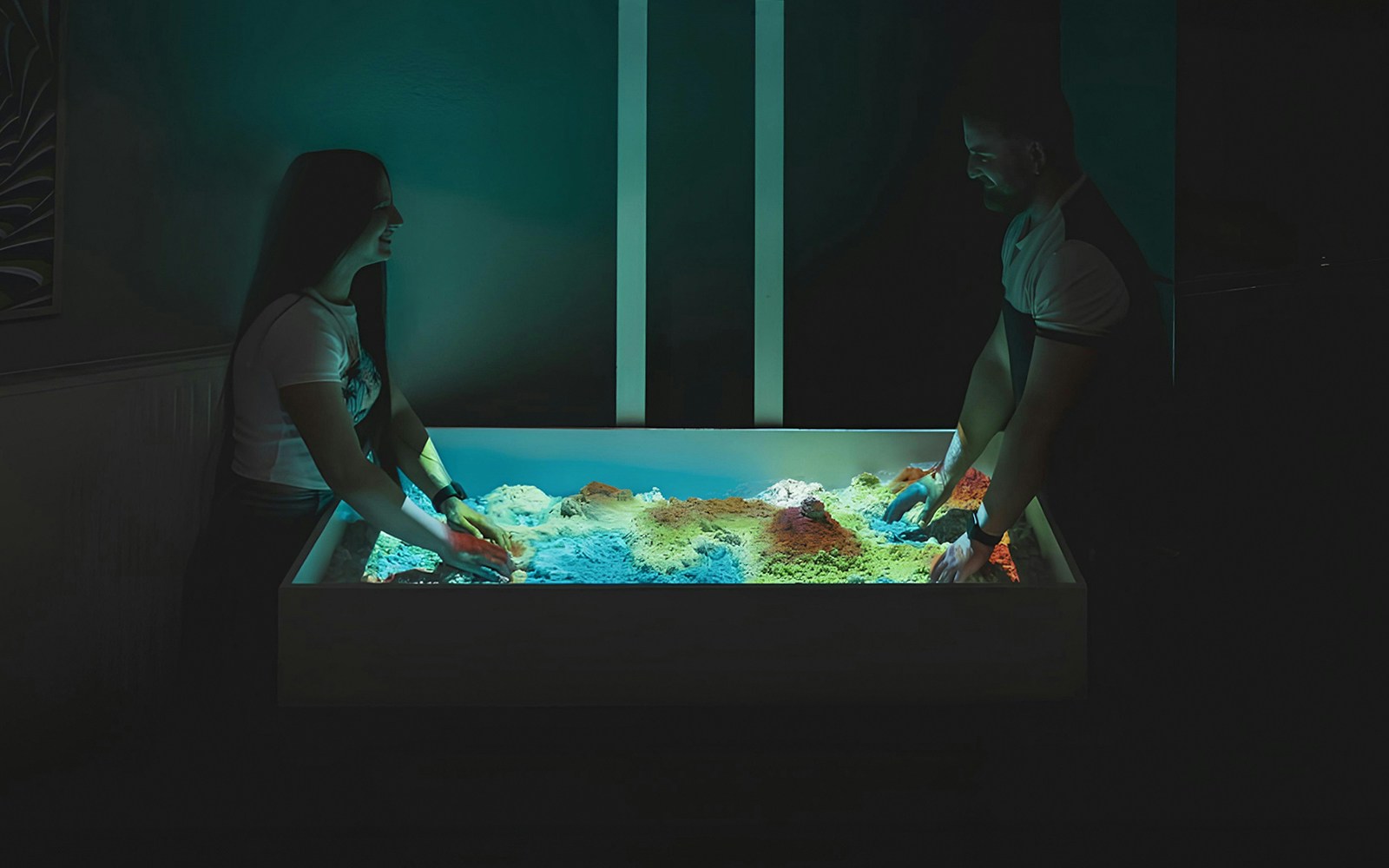 People engaging with interactive sandbox exhibit at DeJa Vu Museum.