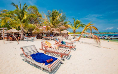 Sun loungers on Koh Samui beach with palm trees and speedboats in the background.