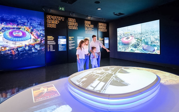 Family exploring interactive exhibit at Spotify Camp Nou Barça Museum.