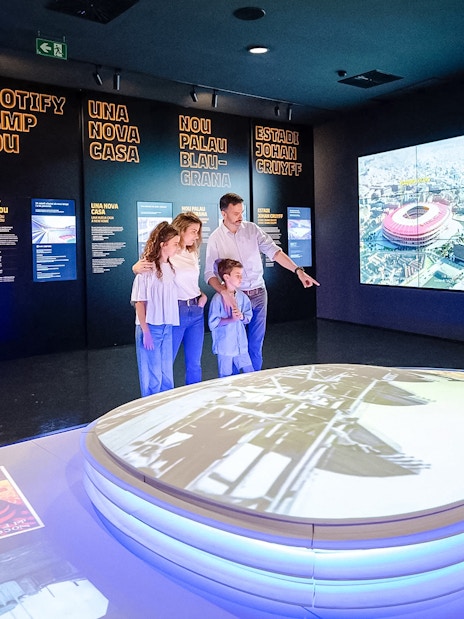 Family exploring interactive exhibit at Spotify Camp Nou Barça Museum.