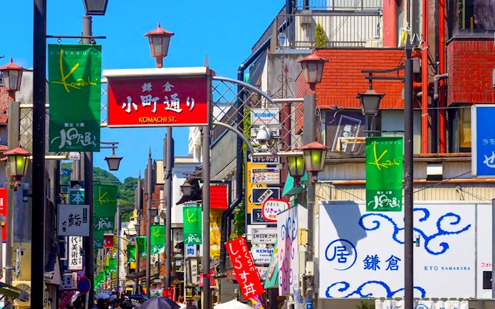 Komachidori Street with colorful shop signs and visitors in Kamakura, Japan.