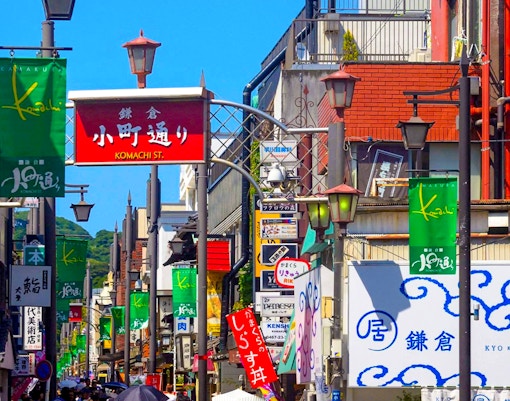 Komachidori Street with colorful shop signs and visitors in Kamakura, Japan.