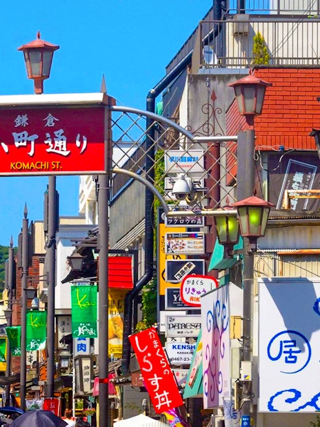 Komachidori Street with colorful shop signs and visitors in Kamakura, Japan.