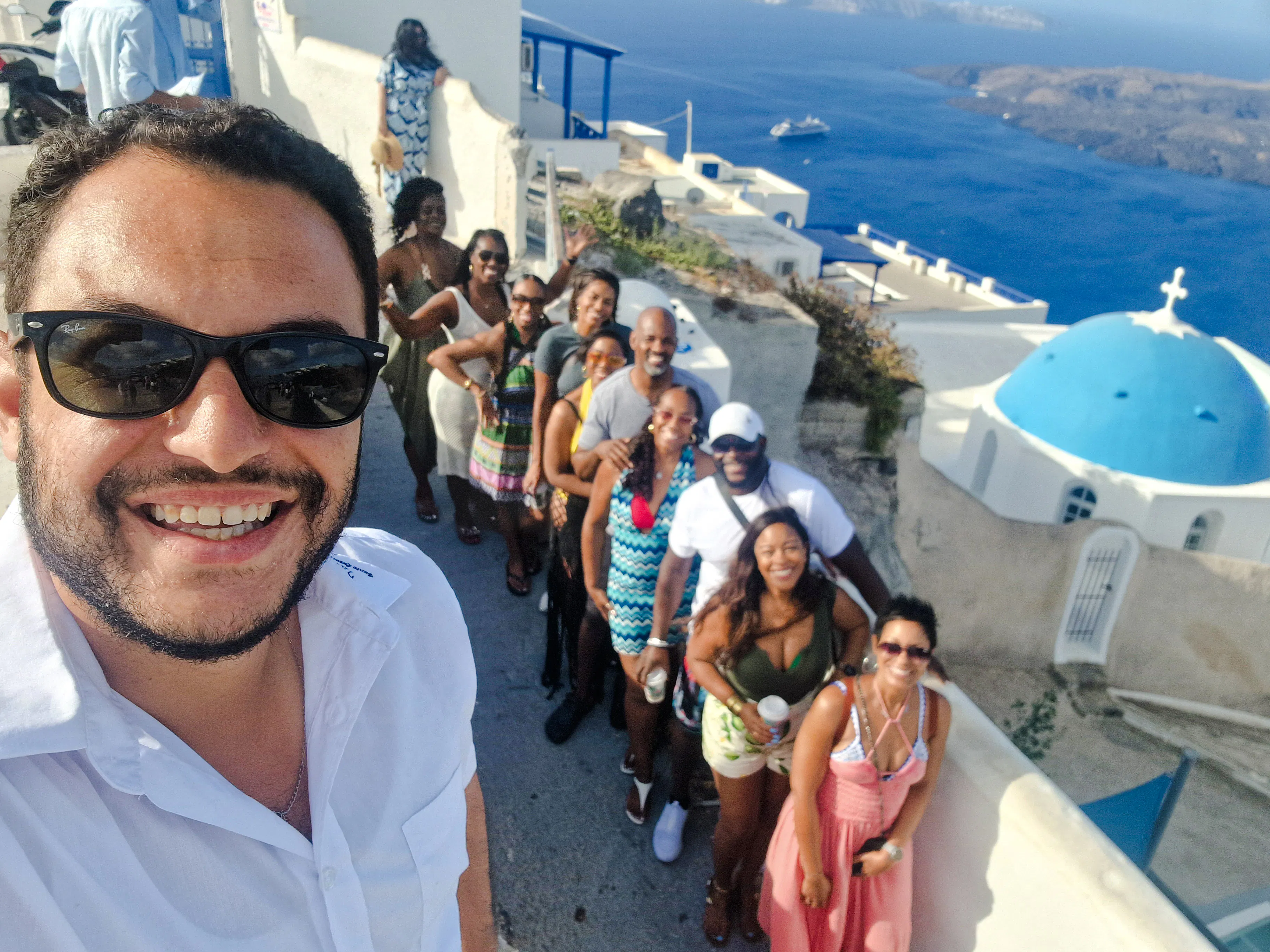 Group enjoying a private tour in Santorini with a view of the iconic blue-domed church and Aegean Sea.