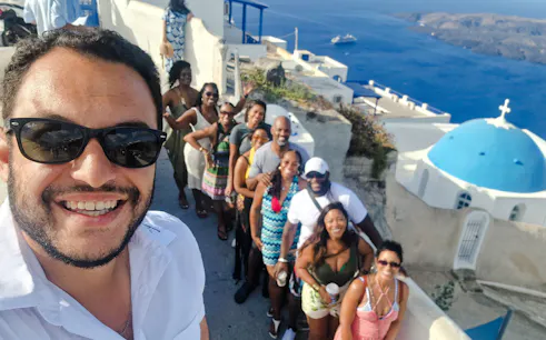 Group enjoying a private tour in Santorini with a view of the iconic blue-domed church and Aegean Sea.