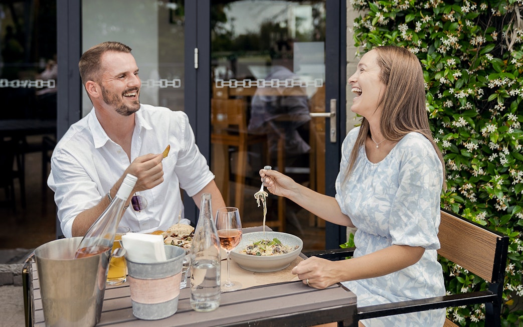 Couple enjoying wine and food at an outdoor table during a Hunter Valley wine tasting tour.