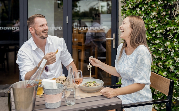Couple enjoying wine and food at an outdoor table during a Hunter Valley wine tasting tour.