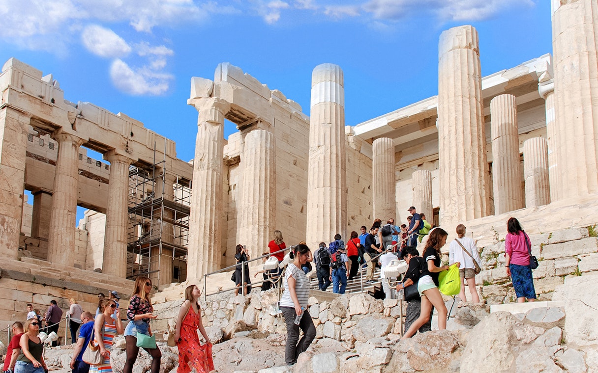Visitors exploring the Acropolis in Athens, Greece, with ancient columns in the background.