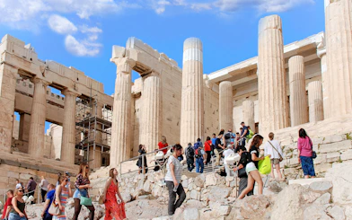 Visitors exploring the Acropolis in Athens, Greece, with ancient columns in the background.