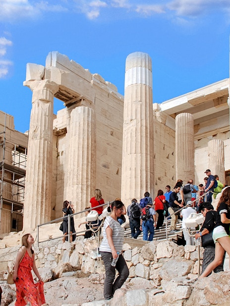 Visitors exploring the Acropolis in Athens, Greece, with ancient columns in the background.