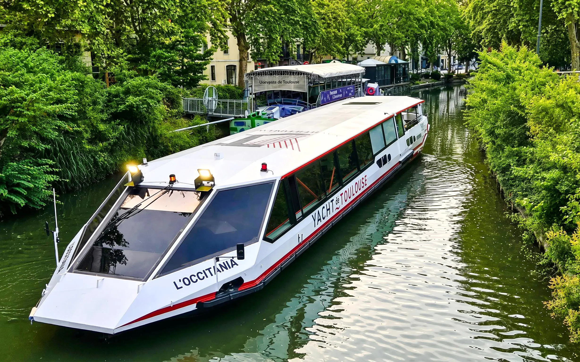 Cruise boat on Canal du Midi in Toulouse with lush greenery and guide commentary.
