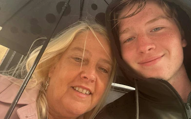 I don't know who these people are, but they are smiling under an umbrella.