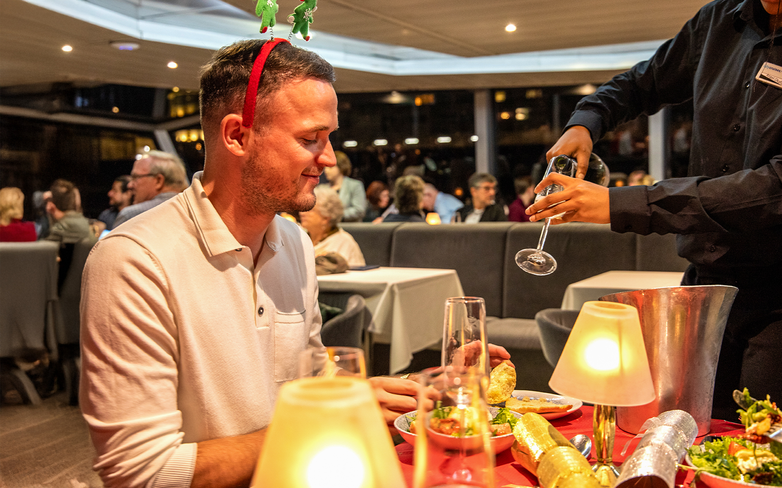 Guests enjoying Christmas dinner on Thames River cruise with festive decorations.