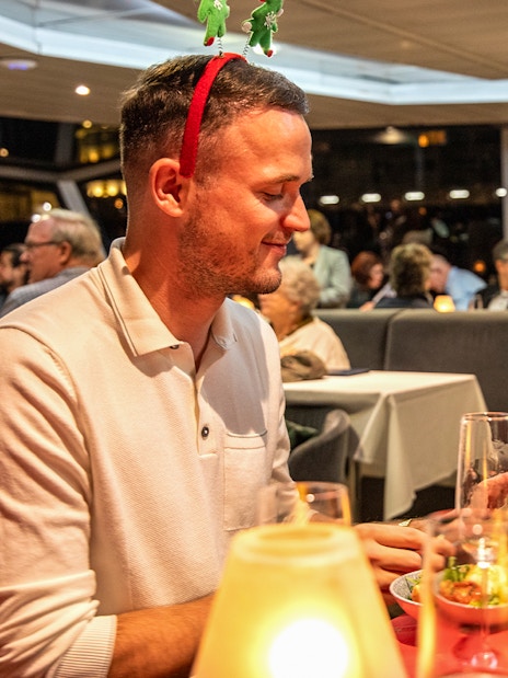 Guests enjoying Christmas dinner on Thames River cruise with festive decorations.