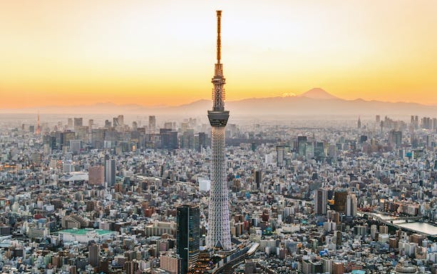 Tokyo Skytree towering over cityscape at sunset.