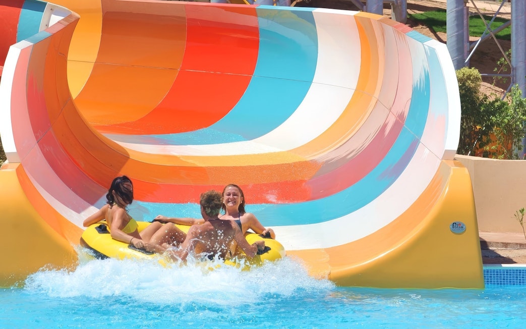 People enjoying a colorful water slide ride at Makadi Water World, Hurghada.